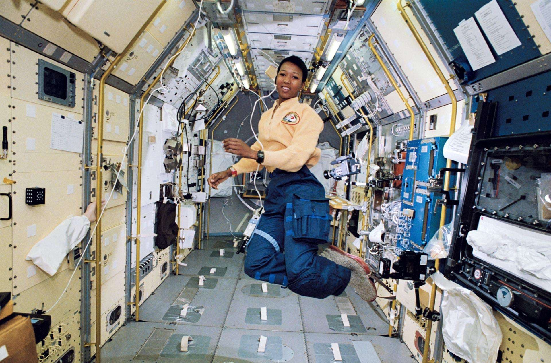A woman in a space suit floats in the vastness of space.